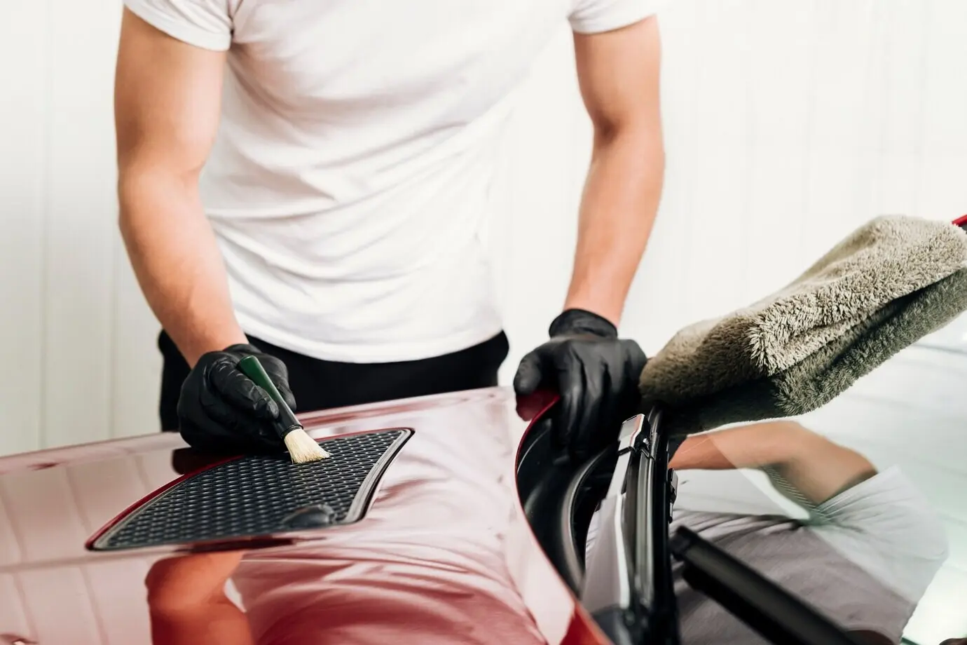 Nahaufnahme einer Person beim Reinigen der Außenfläche eines Autos.